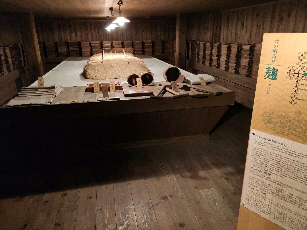 板張りの部屋に麹づくりの台と道具が並ぶ展示