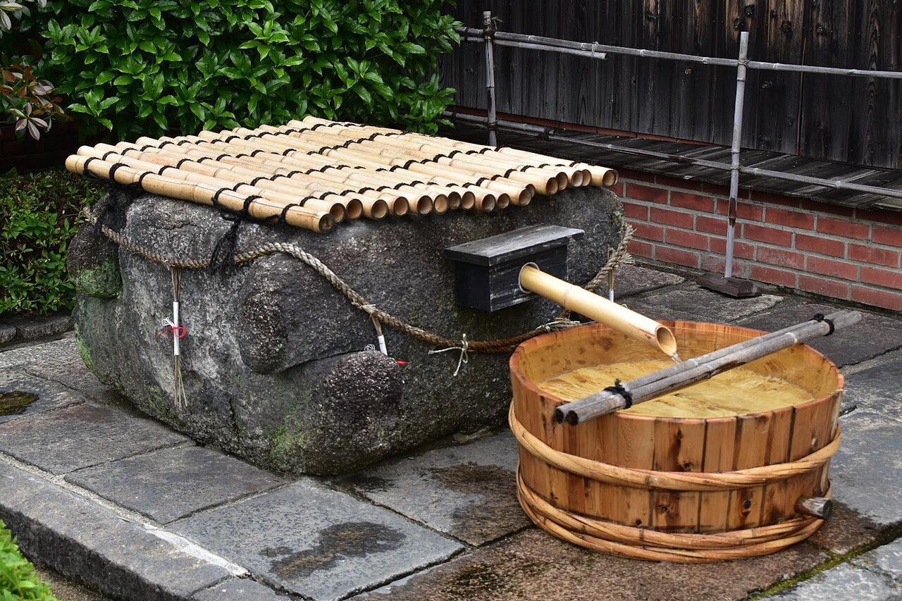 石組みの井戸から木の桶へ水が注ぐ様子